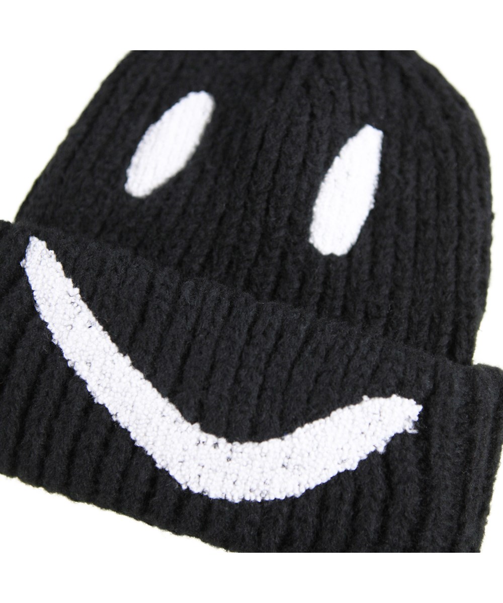 Kim - Black - Zwarte gebreide kindermuts in rib met omslag en geborduurde glimlach in het wit.