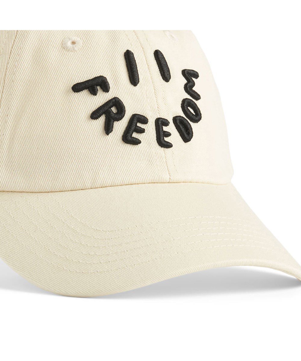 Steel - White Noise - Beige cap with an embroidered smiling face and the text 'Freedom' embroidered as a mouth for children.