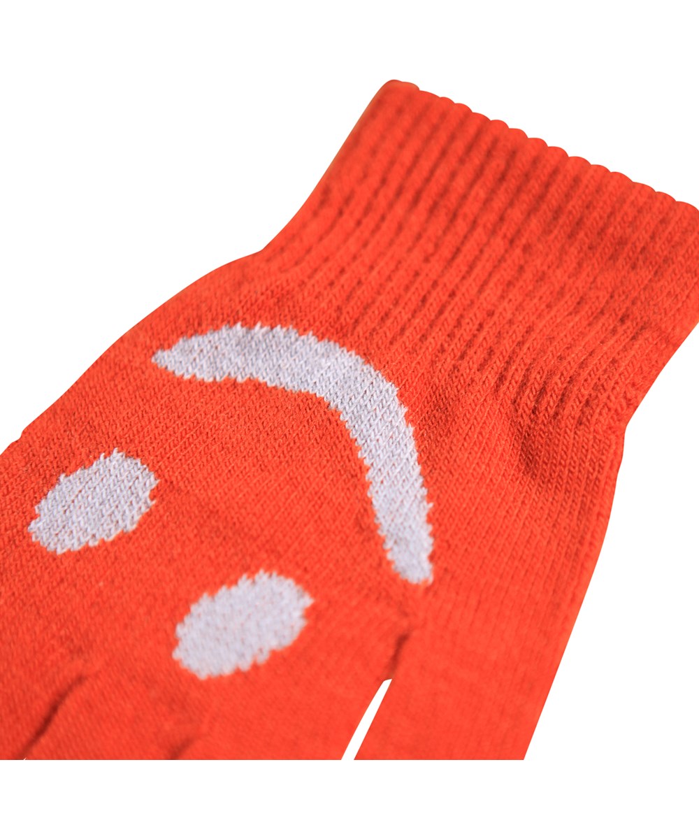 Kello - Rising Sun - 2er-Pack gestrickte Handschuhe für Kinder. Ein Paar ist grau und lila, während das andere Paar rot mit einem beigen lächelnden Gesicht ist.