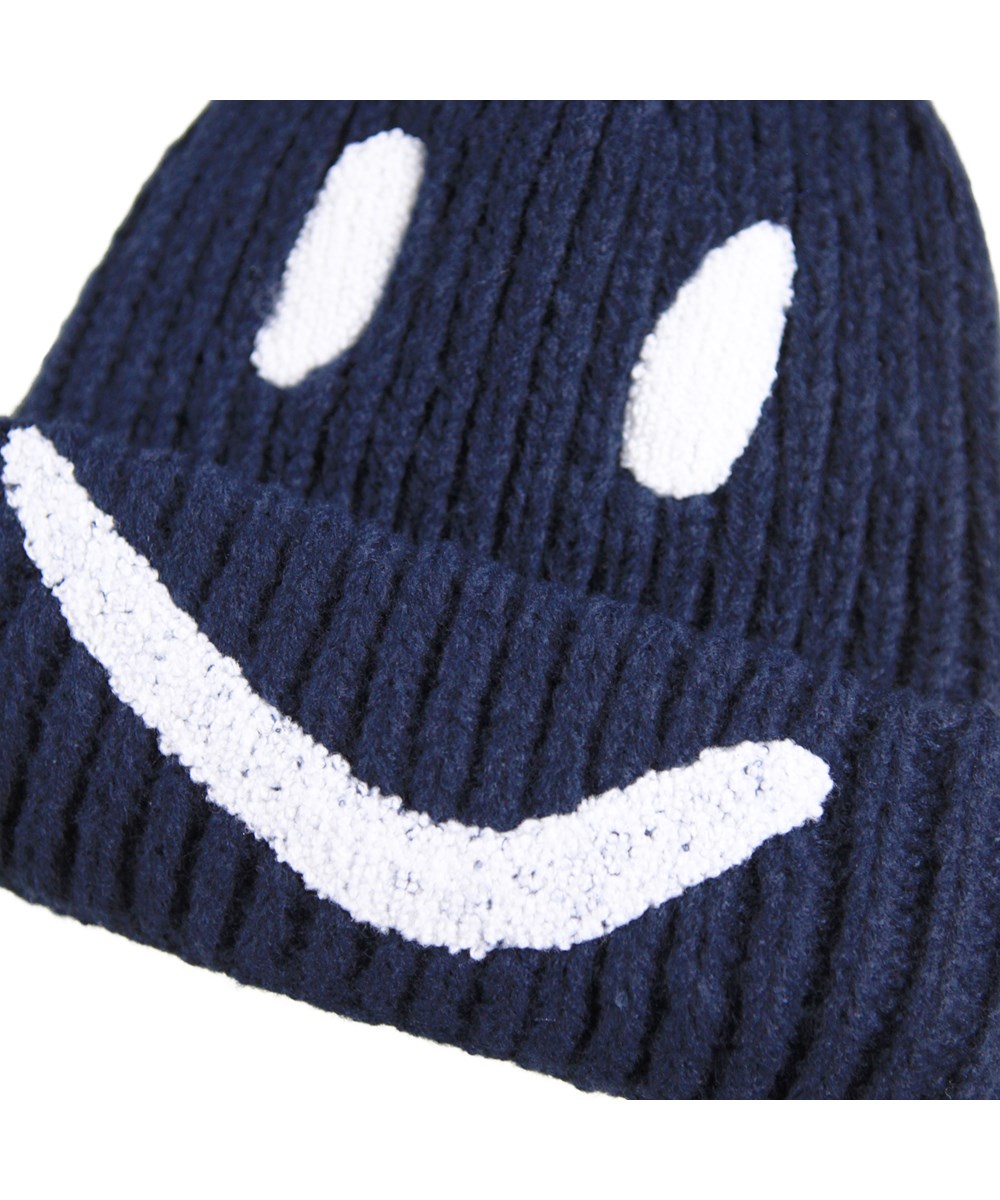 Kim - Night Navy - Dark blue rib-knitted beanie for children with ropp up and embroidered smile in white.