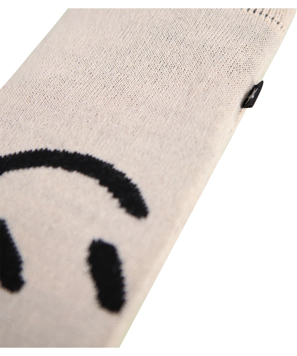 Snowfall - Vanilla - Off-white knitted mittens with a black smiling face for children.