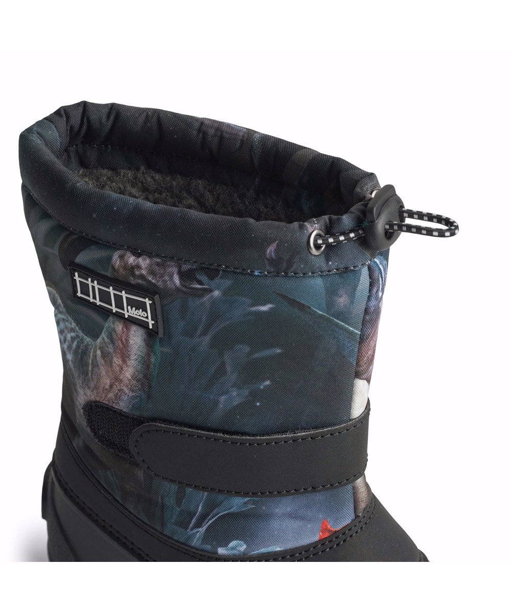 Driven - Dino In Space - Practical winter boots for children with a sturdy and non-slip black sole and a space print of dinosaurs in shades of blue, green, and brown.