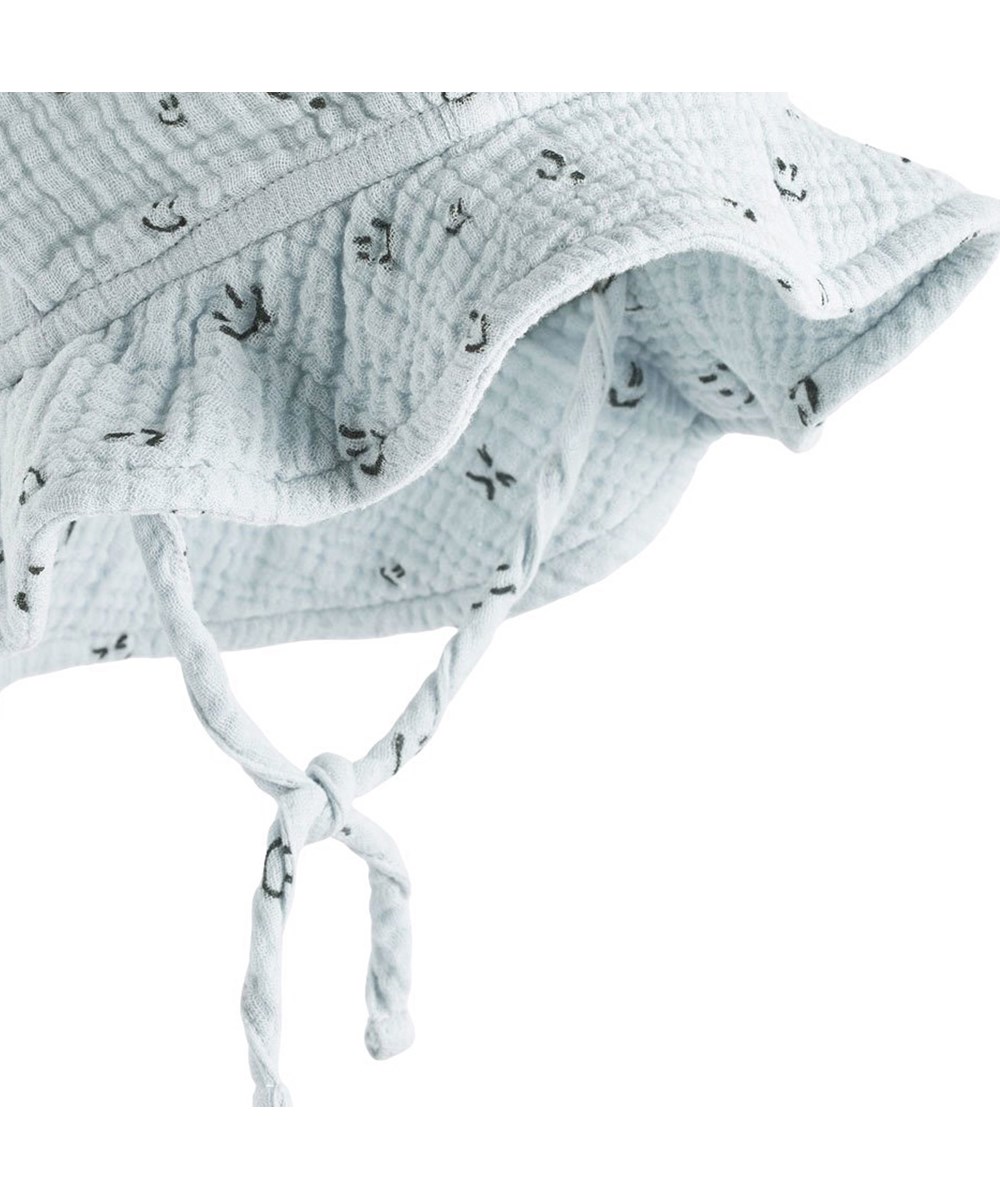 Noel - Moods - Lyseblå babyhat med skygge i økologisk bomuld og print af smilende ansigter. 