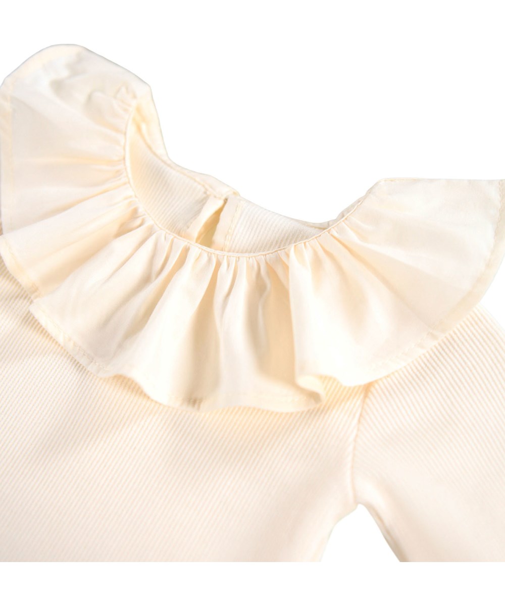 Faye - Buttercream - Krämfärgad långärmad body i ribbad ekologisk bomull med stor krage för baby.