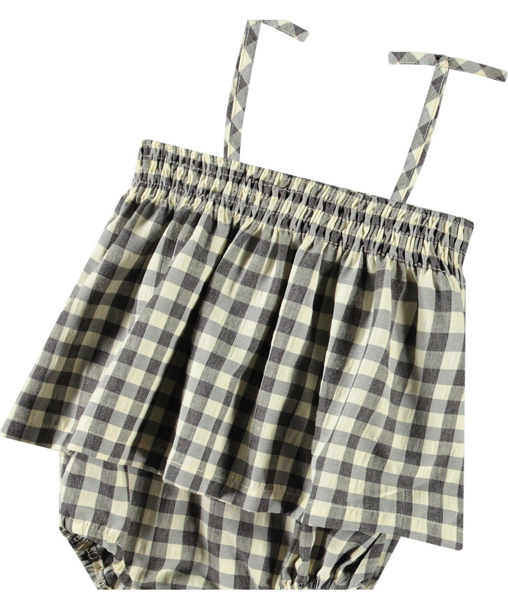 Flora - Sun Check - Rutig sommaroverall för baby i ekologisk bomull. Overallen har tunna axelband och inga ben.