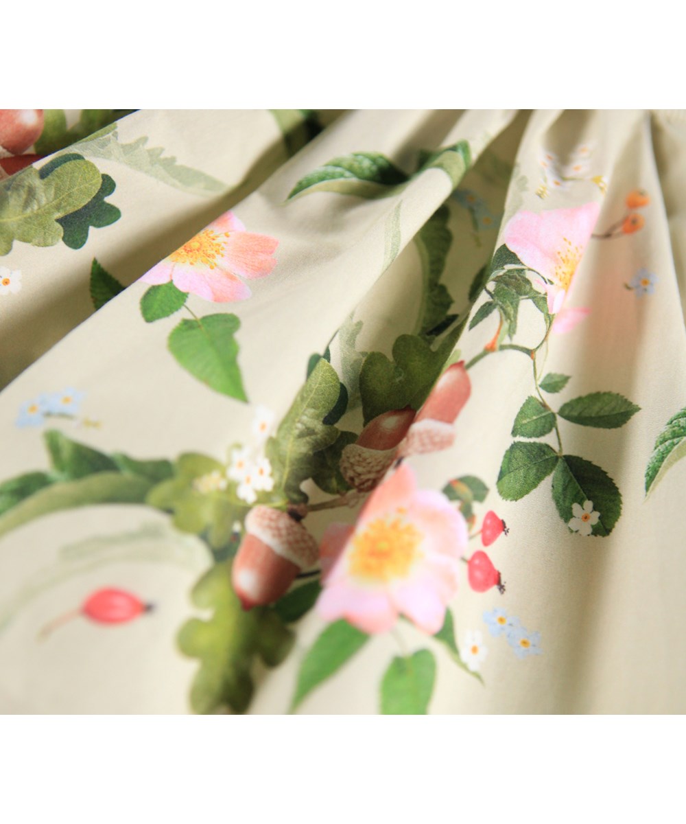 Candi - Floral Heart - Långärmad babyklänning i ekologisk bomull. Klänningen är ljusgrön med ett blommigt mönster.