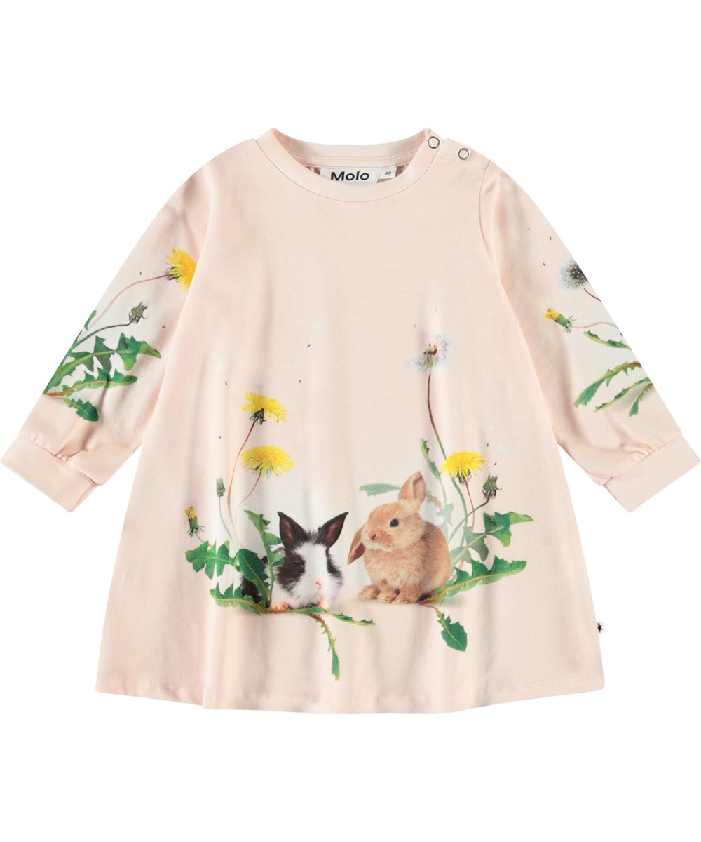 Corey - Rabbit Garden - En A-linjeformad klänning i ekologisk bomull för en baby. Klänningen är rosa med kaniner och maskrosor.