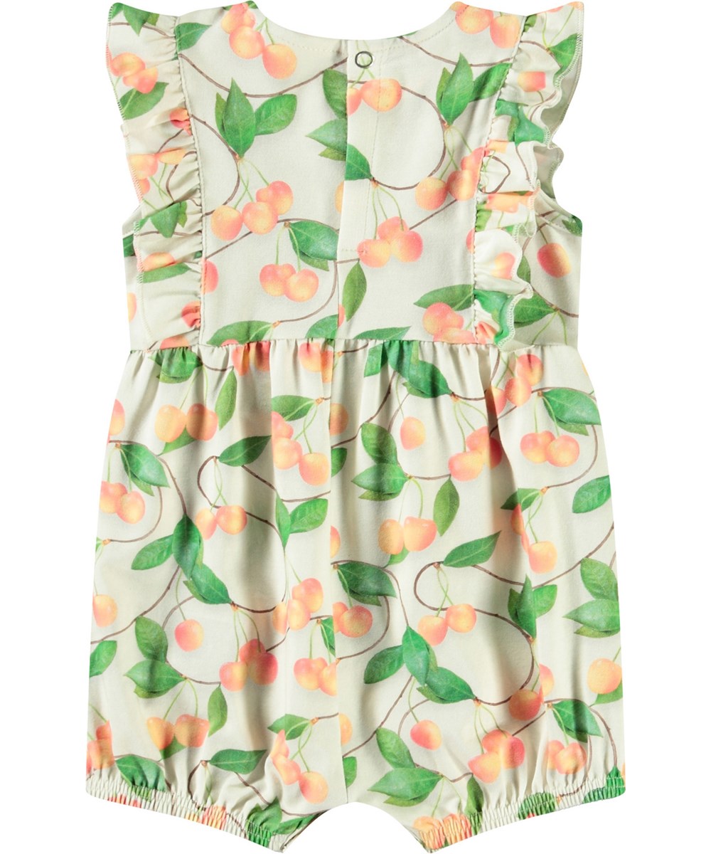Felicia - Sweet Cherries - Jumpsuit with short sleeves and ruffles in organic cotton for baby. It has a cherry print.