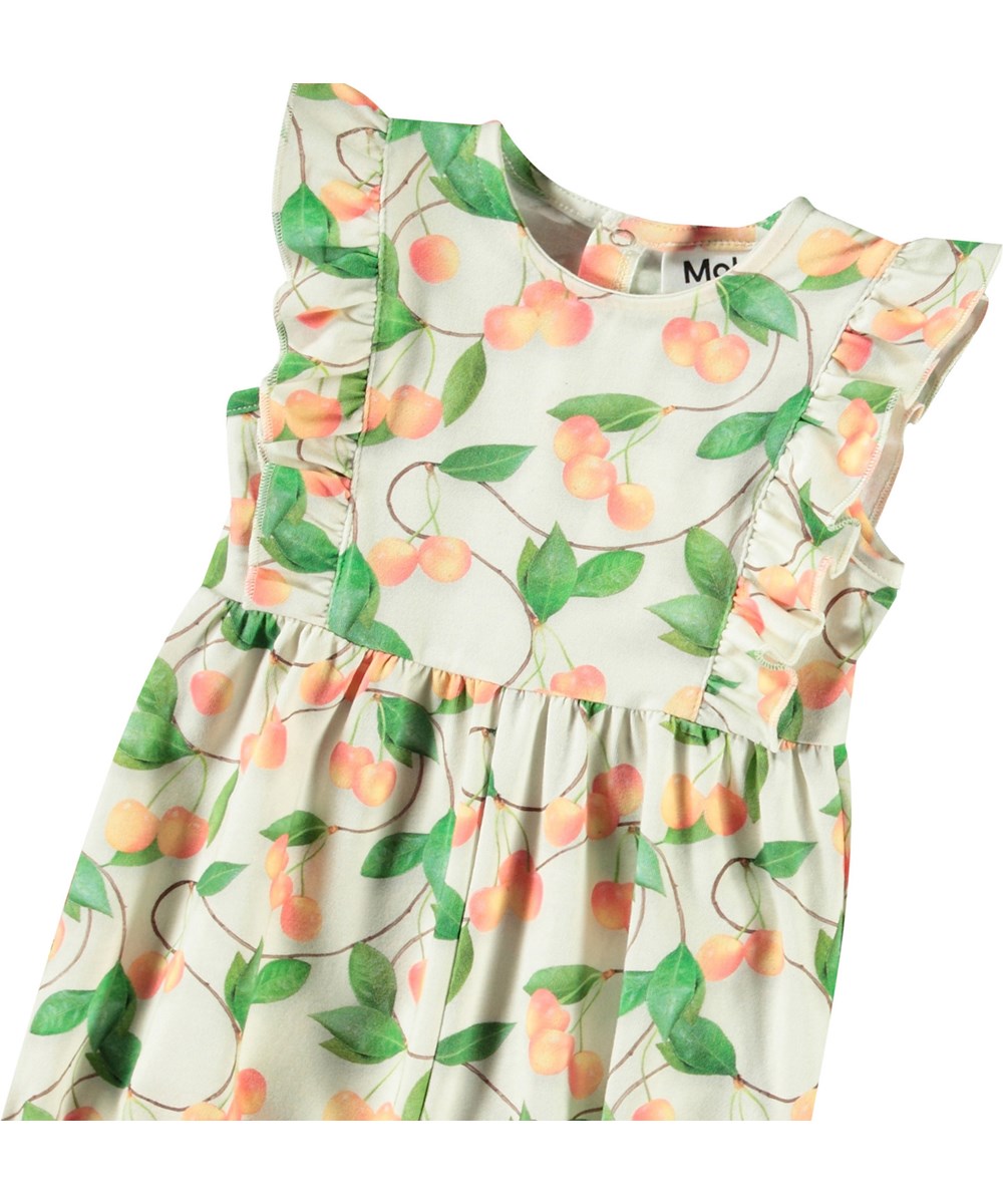 Felicia - Sweet Cherries - Jumpsuit with short sleeves and ruffles in organic cotton for baby. It has a cherry print.