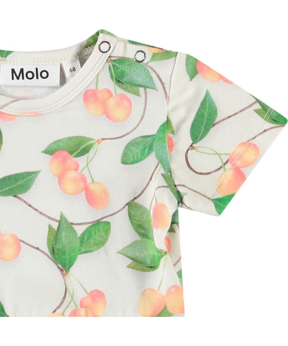 Frannie - Sweet Cherries - Baby's light coloured bodysuit in organic cotton. Short-sleeved with peplum skirt and cherry print.