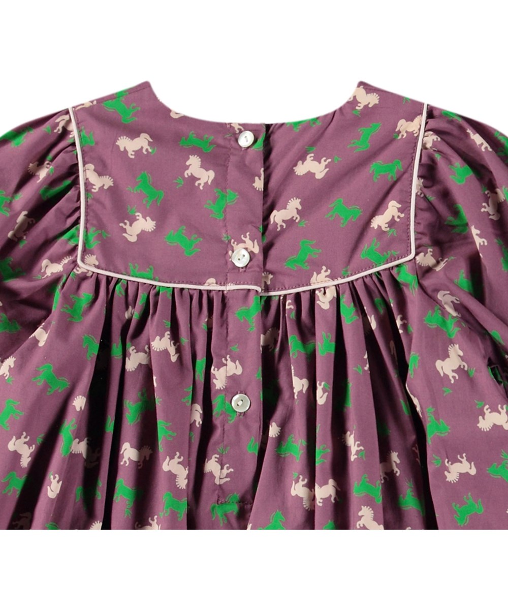 Clair - Giddy-Up Baby - Poplin dress in organic cotton for baby. The dress is purple with horse print in green and beige.