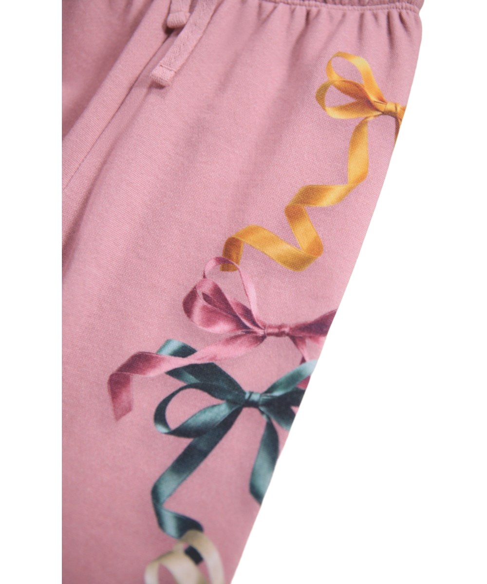 Simeon - Ribbon Play - Soft dark pink pants for the little ones made of organic cotton with a print of colorful ribbons and bows.