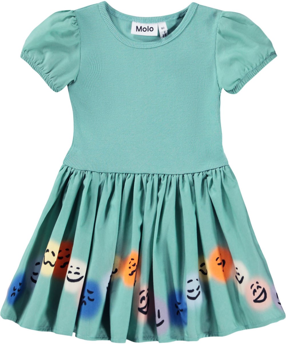 Caitlin - Wavy Moods - Grünes Popelinekleid für die Kleinen aus Öko-Baumwolle mit einem Druck von Gesichtern in verschiedenen Stimmungen.