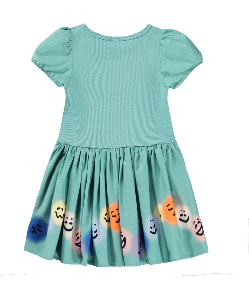 Caitlin - Wavy Moods - Grünes Popelinekleid für die Kleinen aus Öko-Baumwolle mit einem Druck von Gesichtern in verschiedenen Stimmungen.