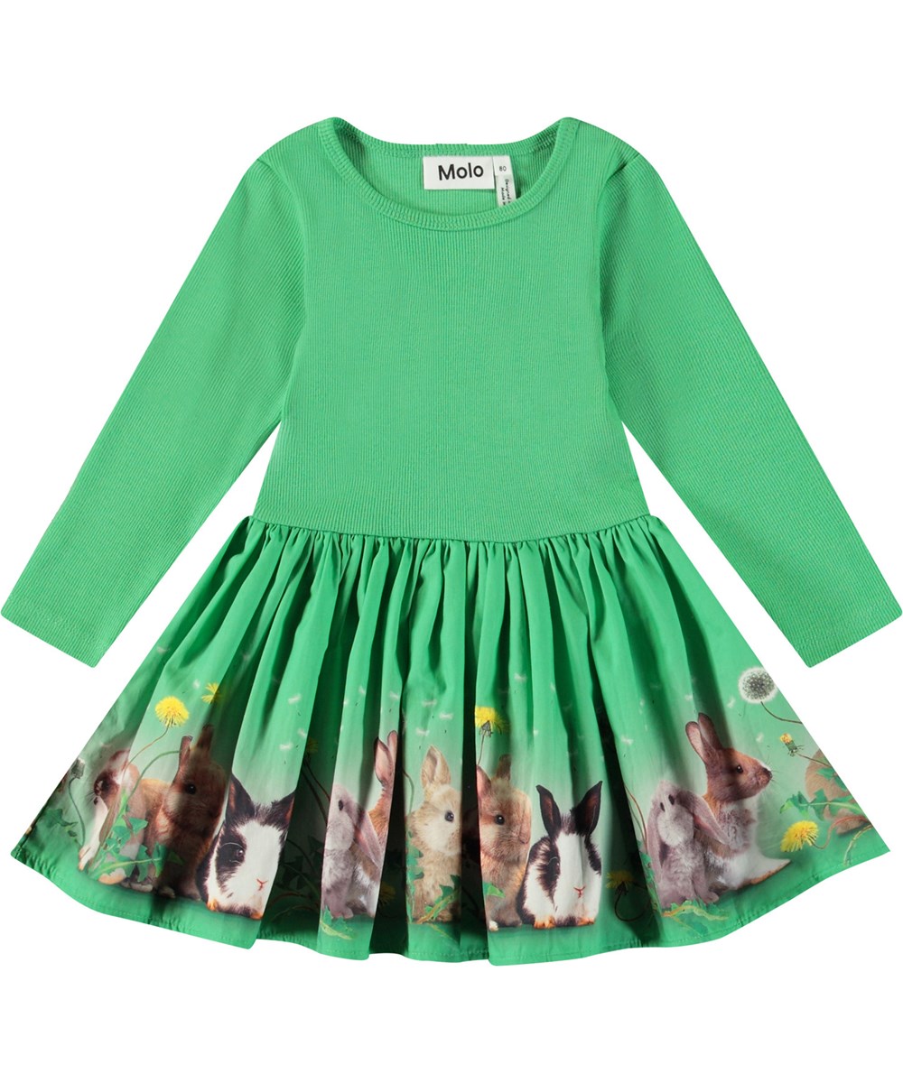 Candi - Bonnie Patch - Langärmeliges Kleid für Babys aus Öko-Baumwolle. Das Kleid ist grün mit einem Aufdruck von Hasen und Löwenzahn.