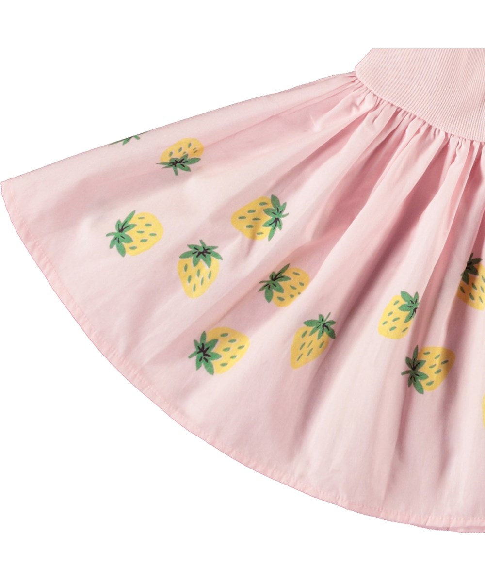 Carin - Bouncy Berries - Kleid für Baby aus Öko-Baumwolle. Das Kleid ist rosa mit einem Druck von gelben Erdbeeren.