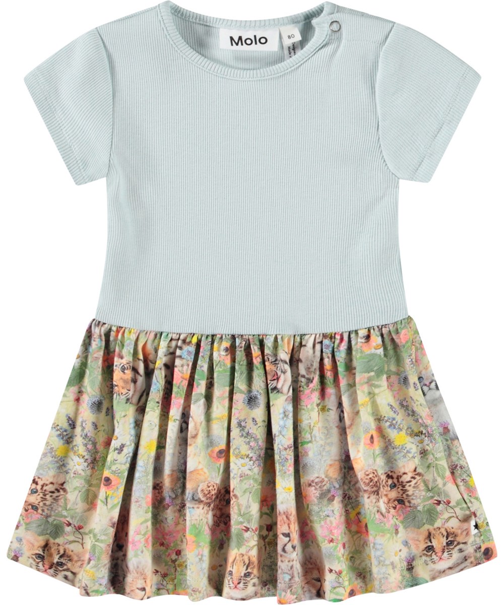 Catja - Meadow Cubs - Kleid für Baby aus Öko-Baumwolle. Das Kleid ist hellblau mit einem bunten Druck von Tierbabys in einem Blumenbeet.