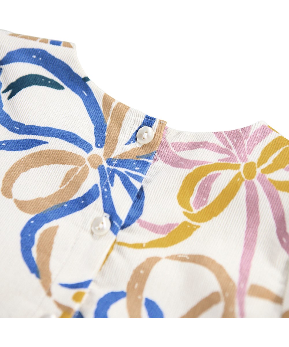 Chantelle - Festivity Bows - Off-weißes Kleid für die Kleinen aus Öko-Baumwoll-Velours mit einem Druck bunter Bänder.