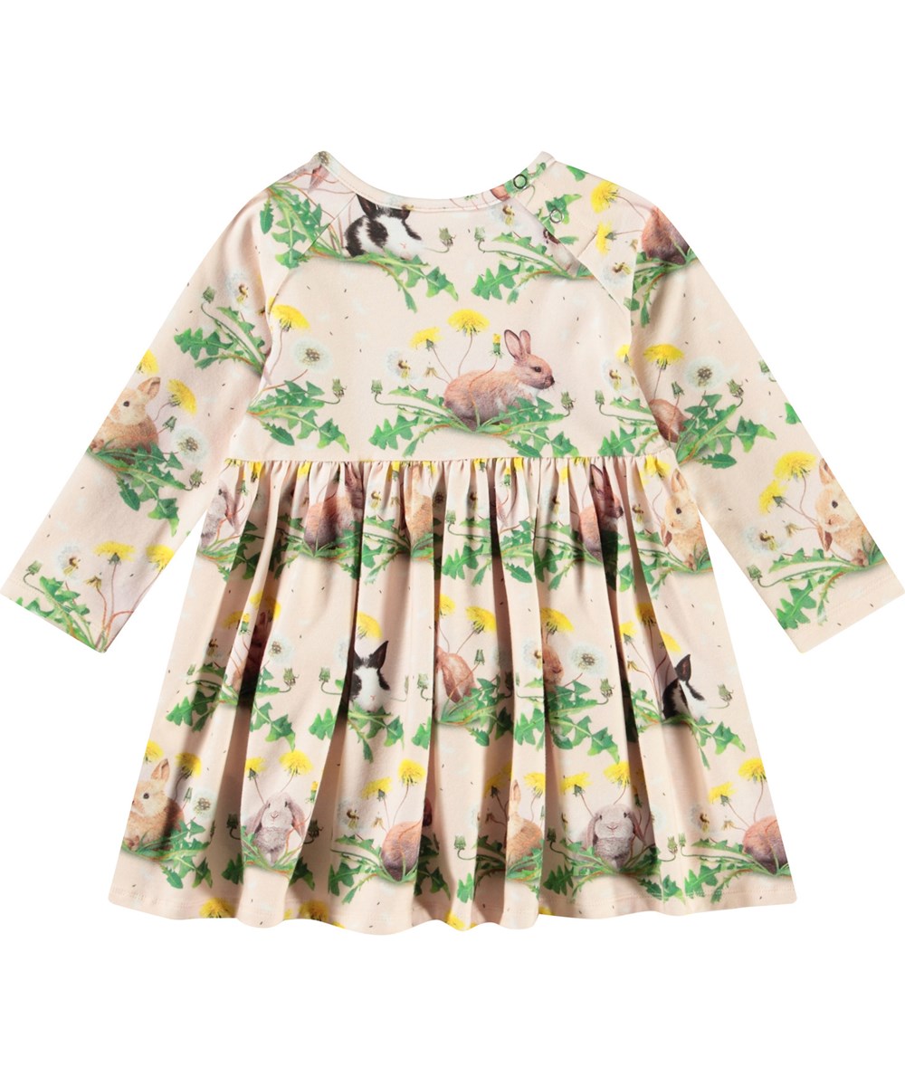 Charmaine - Bunnies United - Langärmeliges Kleid für Babys aus Öko-Baumwolle. Das Kleid hat einen Aufdruck von Hasen und Löwenzahn.