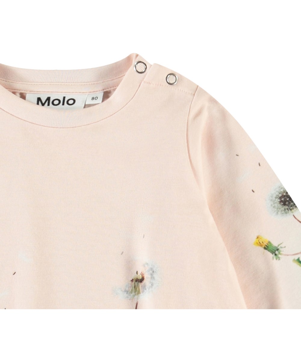 Corey - Rabbit Garden - A-Linien-Kleid aus Öko-Baumwolle für ein Baby. Das Kleid ist rosa mit einem Druck von Kaninchen und Löwenzahn.