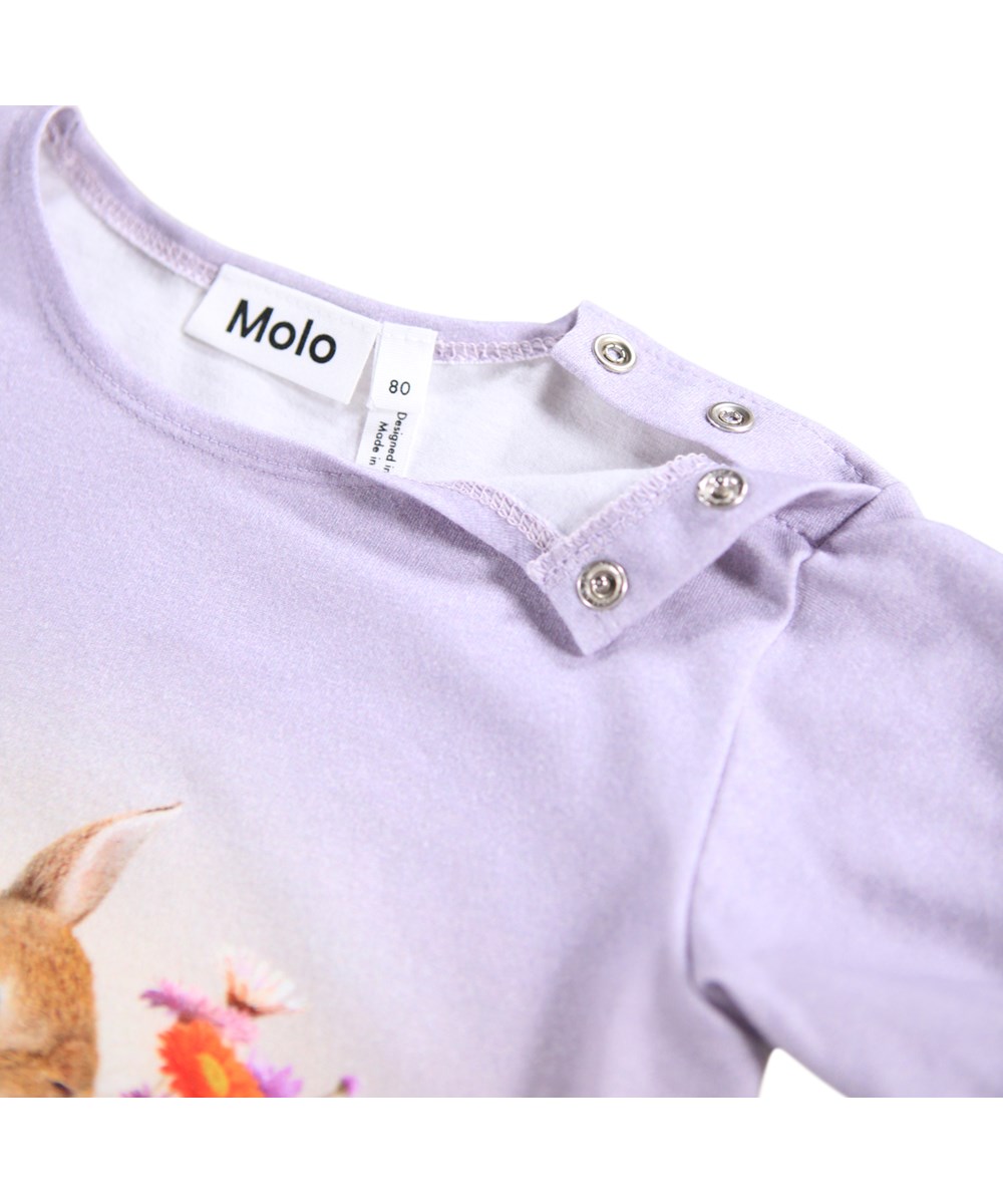 Eline - Dressy Rabbit - Hellviolett und rosa T-Shirt für die Kleinen mit Rüschen-Details aus Öko-Baumwolle. Das T-Shirt hat einen Aufdruck eines kleinen Hasen und Blumen.