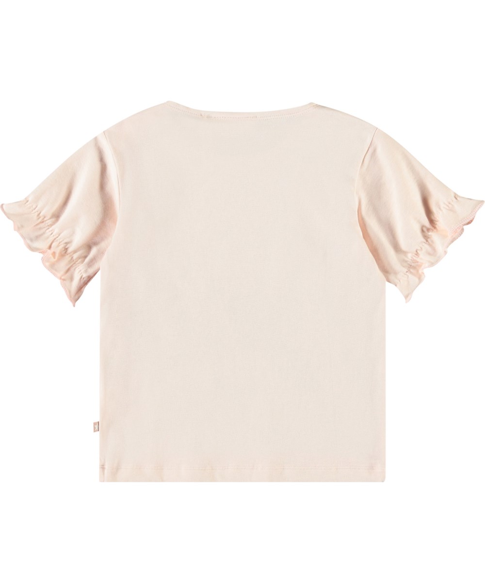 Eline - Rabbit Friends - T-Shirt mit Rüschen-Details aus Öko-Baumwolle für Babys. Das T-Shirt ist rosa mit einem Vordruck von Hasen und Löwenzahn.