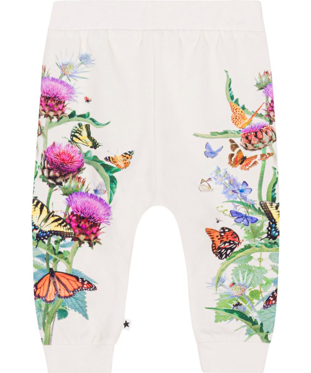 Susanne - Garden Pants - Voor kleine kinderen een gebroken witte jersey broek van biologisch katoen met een print van paarse en rode artisjokbloemen met kleurrijke vlinders 