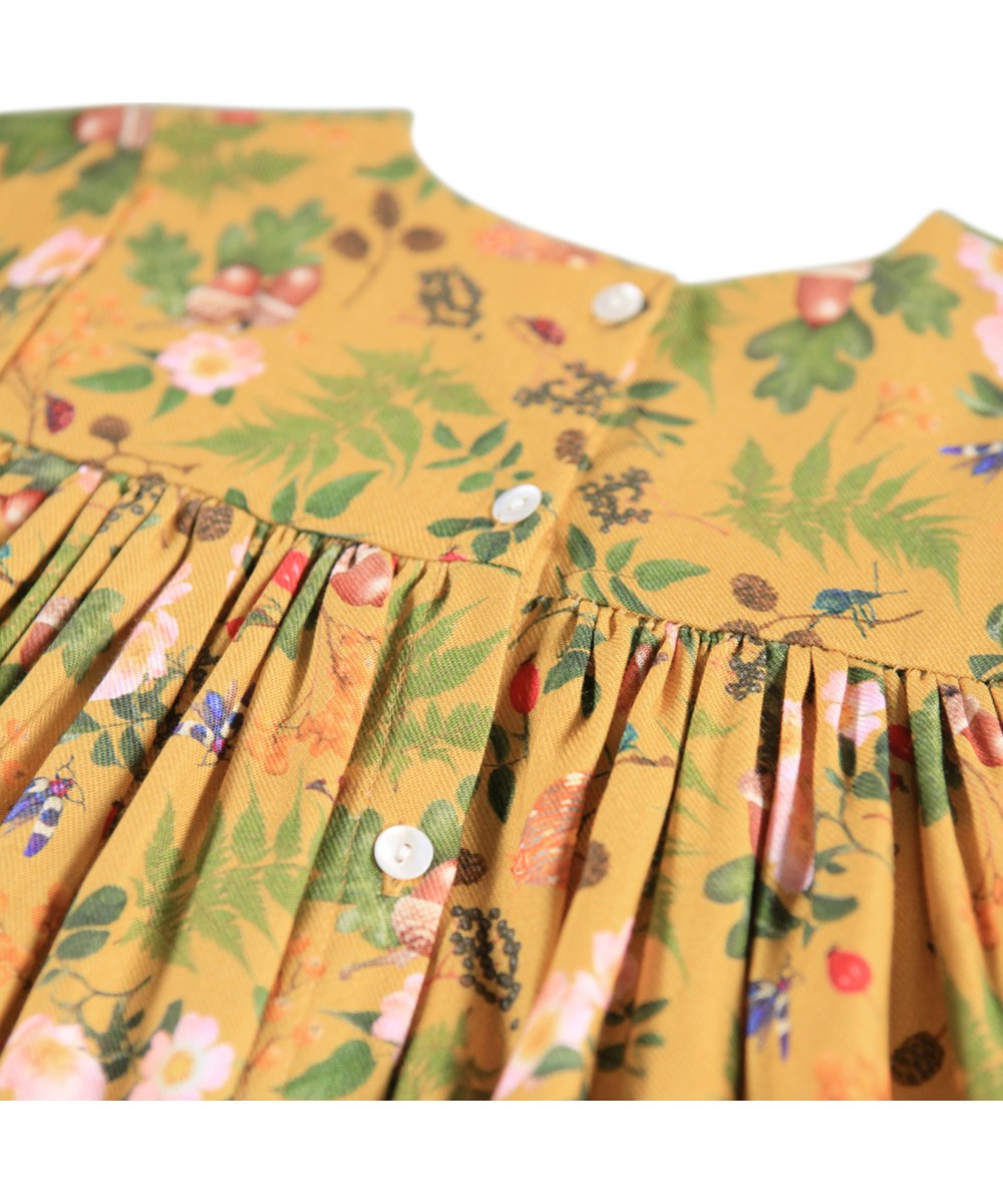 Claire - Foraging - Mooi gele jurk voor de kleintjes gemaakt van viscose met een print van bloemen, bessen en insecten.