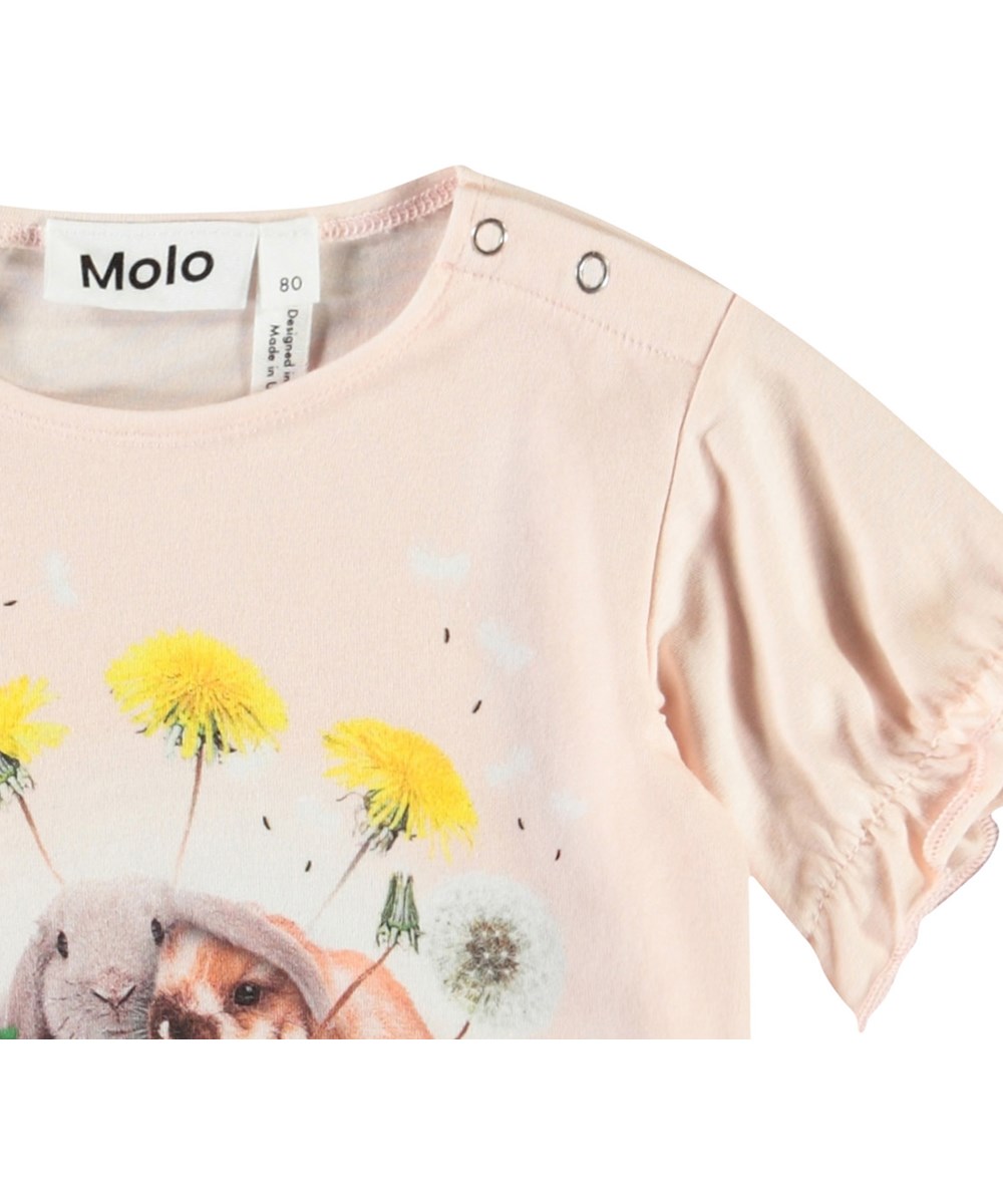 Eline - Rabbit Friends - T-shirt med flæsedetaljer i økologisk bomuld til baby. T-shirten er lyserød med et frontprint af kaniner og mælkebøtter,