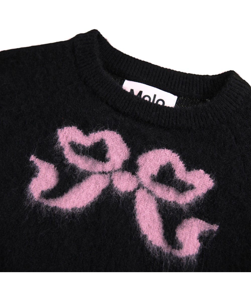 Gilby - Fancy Bows - Striktrøje i uld til baby. Trøjen er sort med multifarvede vævede sløjfer på front og bag.