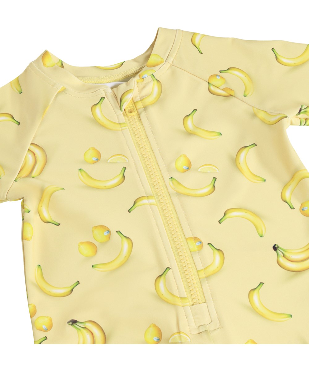 Neka LS - Lemon Banana - Gul badedragt med frugtprint til baby og børn med lange ærmer og korte ben i genanvendt polyester og UV-beskyttelse 50+.