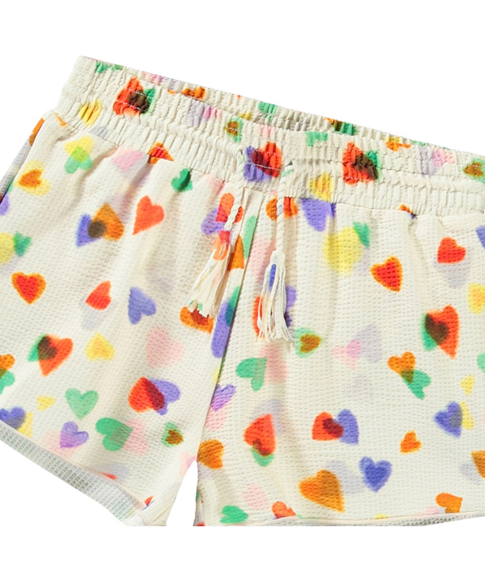 Nicci - Rainbow Hearts - Hvide badeshorts til aktive børn med UV-beskyttelse 50+ og et farverigt hjerte print