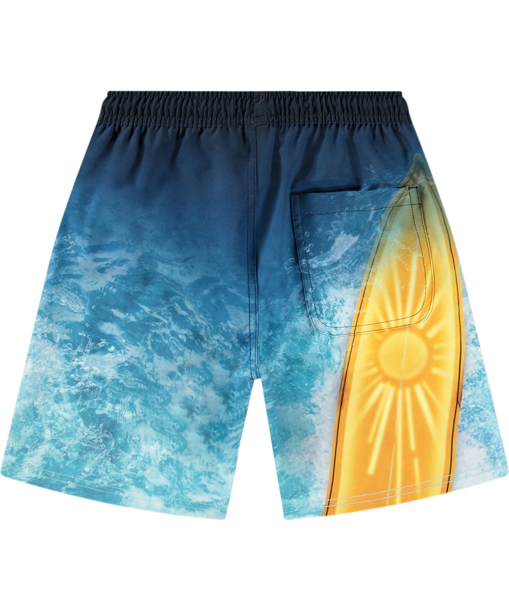 Nilson - Surf Art Blue Chill - Knælange blå badeshorts til aktive børn i genanvendt polyester med UV-beskyttelse 50+.
