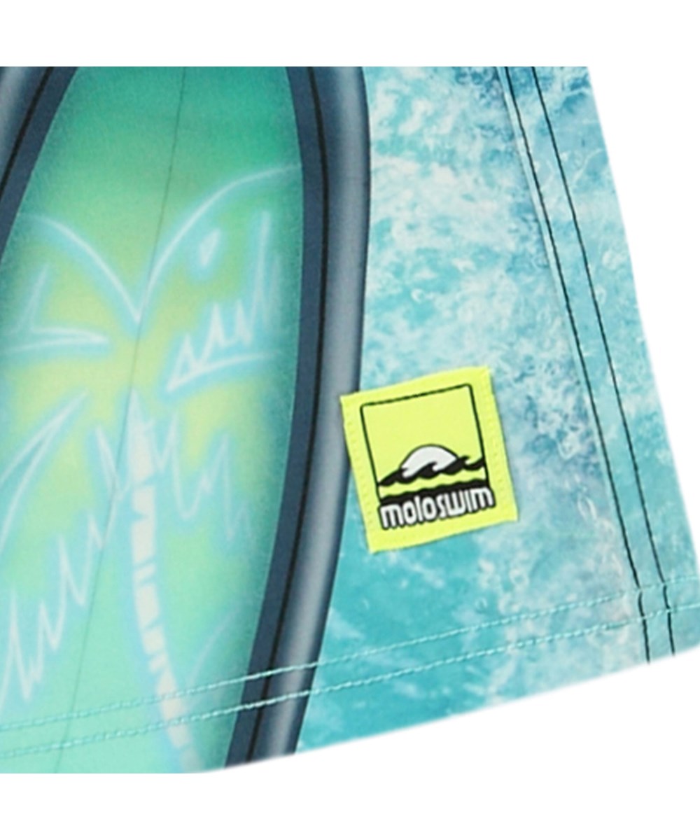 Nilson - Surf Art Blue Chill - Knælange blå badeshorts til aktive børn i genanvendt polyester med UV-beskyttelse 50+.