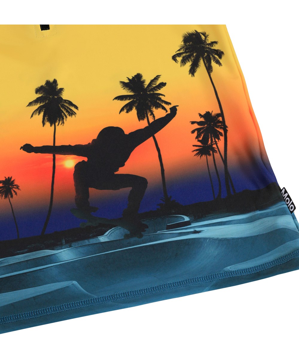 Noble - Sunset Skate - Gul badebluse med skateprint og lynlås til børn fremstillet i genanvendt polyester med UV-beskyttelse 50+.