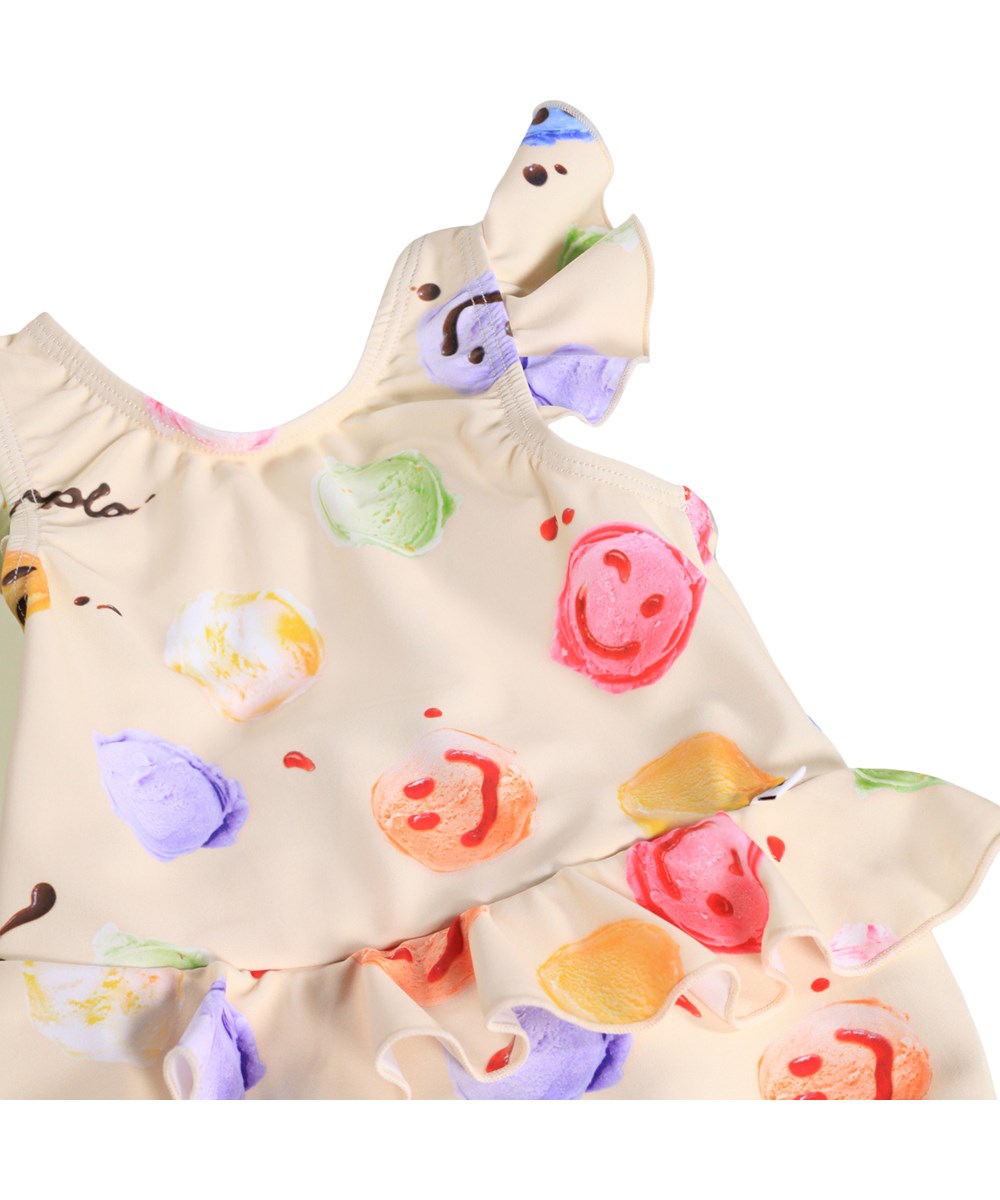 Nandini - Smile Scoops - Gräddfärgad, läckagesäker baddräkt för bebisar med glassmönster i återvunnen polyester med UV-skydd 50+.