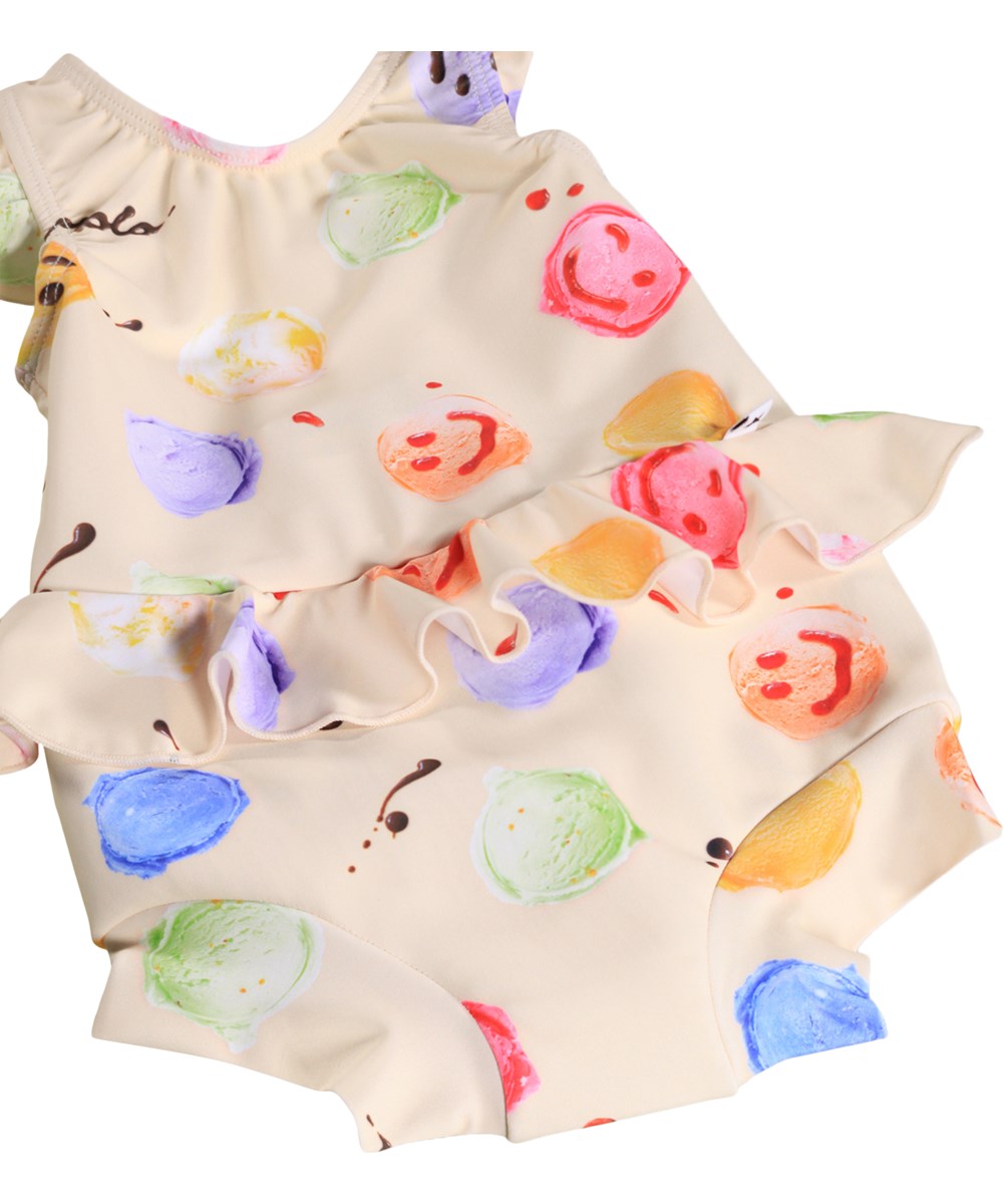 Nandini - Smile Scoops - Gräddfärgad, läckagesäker baddräkt för bebisar med glassmönster i återvunnen polyester med UV-skydd 50+.