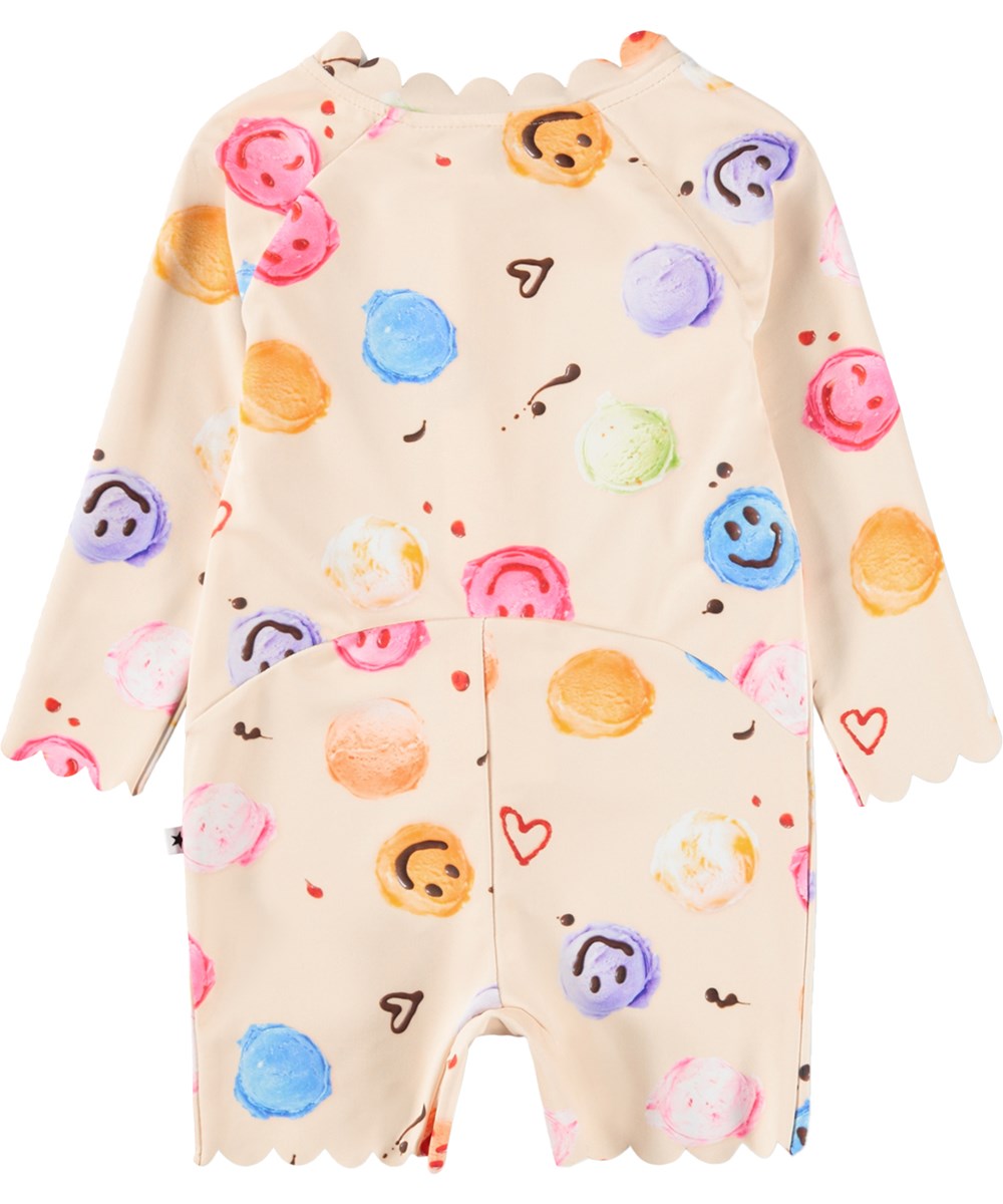 Nigella - Smile Scoops - Gräddfärgad baddräkt med glassmönster för de små med långa ärmar och korta ben i återvunnen polyester med UV-skydd 50+.