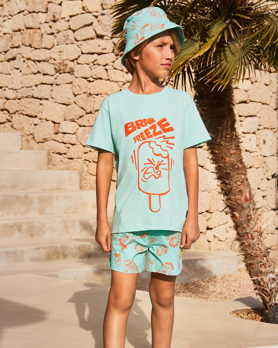 Niko - Brain Freeze - Sportiga, blå badbyxor med orange och tecknat mönster för aktiva barn i återvunnen polyester med UV-skydd 50+.