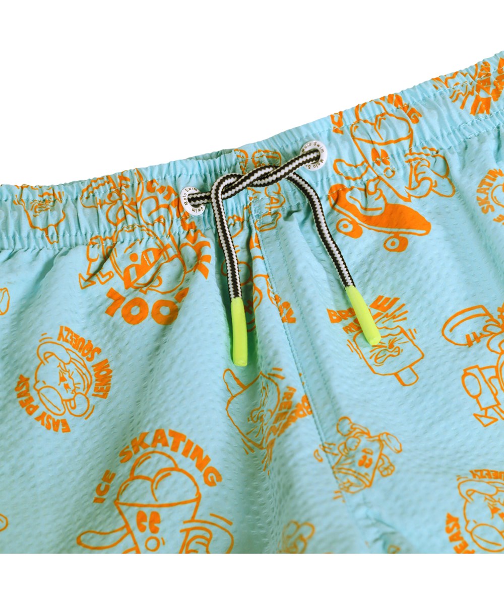 Niko - Brain Freeze - Sportiga, blå badbyxor med orange och tecknat mönster för aktiva barn i återvunnen polyester med UV-skydd 50+.