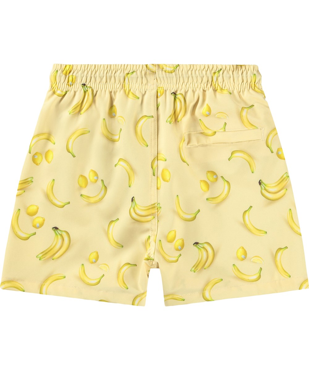 Niko - Lemon Banana - Sportiga, gula badshorts med fruktmönster för aktiva barn i återvunnen polyester med UV-skydd 50+.