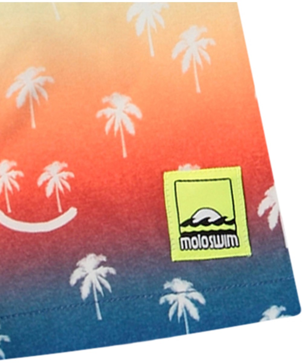 Niko - Palmtree Smile - Regnbågsfärgade sportiga badshorts för aktiva barn i återvunnen polyester med UV-skydd 50+.