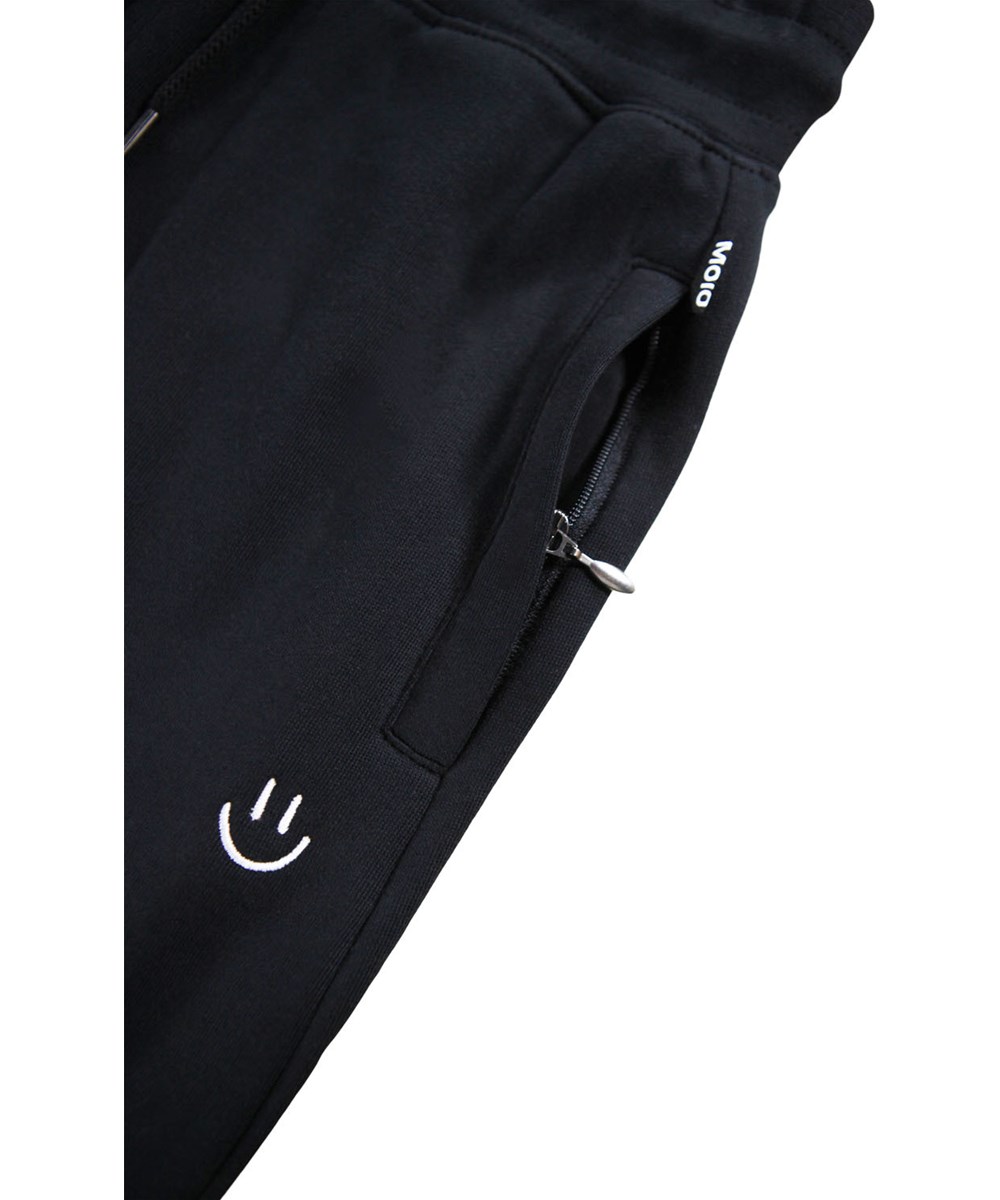 Alvar - Black - Svarta sweatpants i ekologisk bomull med broderat vitt leende ansikte.