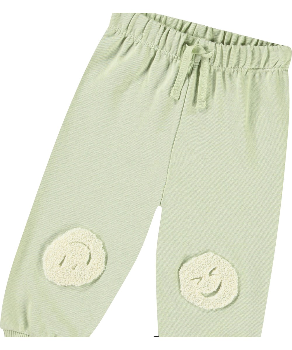 Simeon - Misty Green - Mjuka byxor i ekologisk bomull för baby. Byxorna är ljusgröna med mjuka smileys.