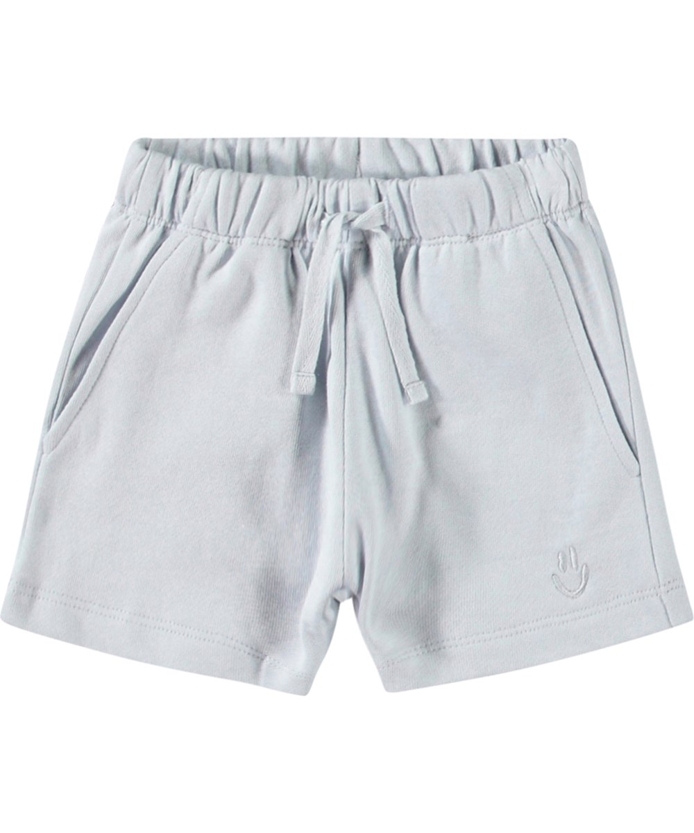 Simms - Skywriting - Mjuka shorts i ekologisk bomull för baby. Dessa shorts är ljusblå med en broderad smiley på ett ben.