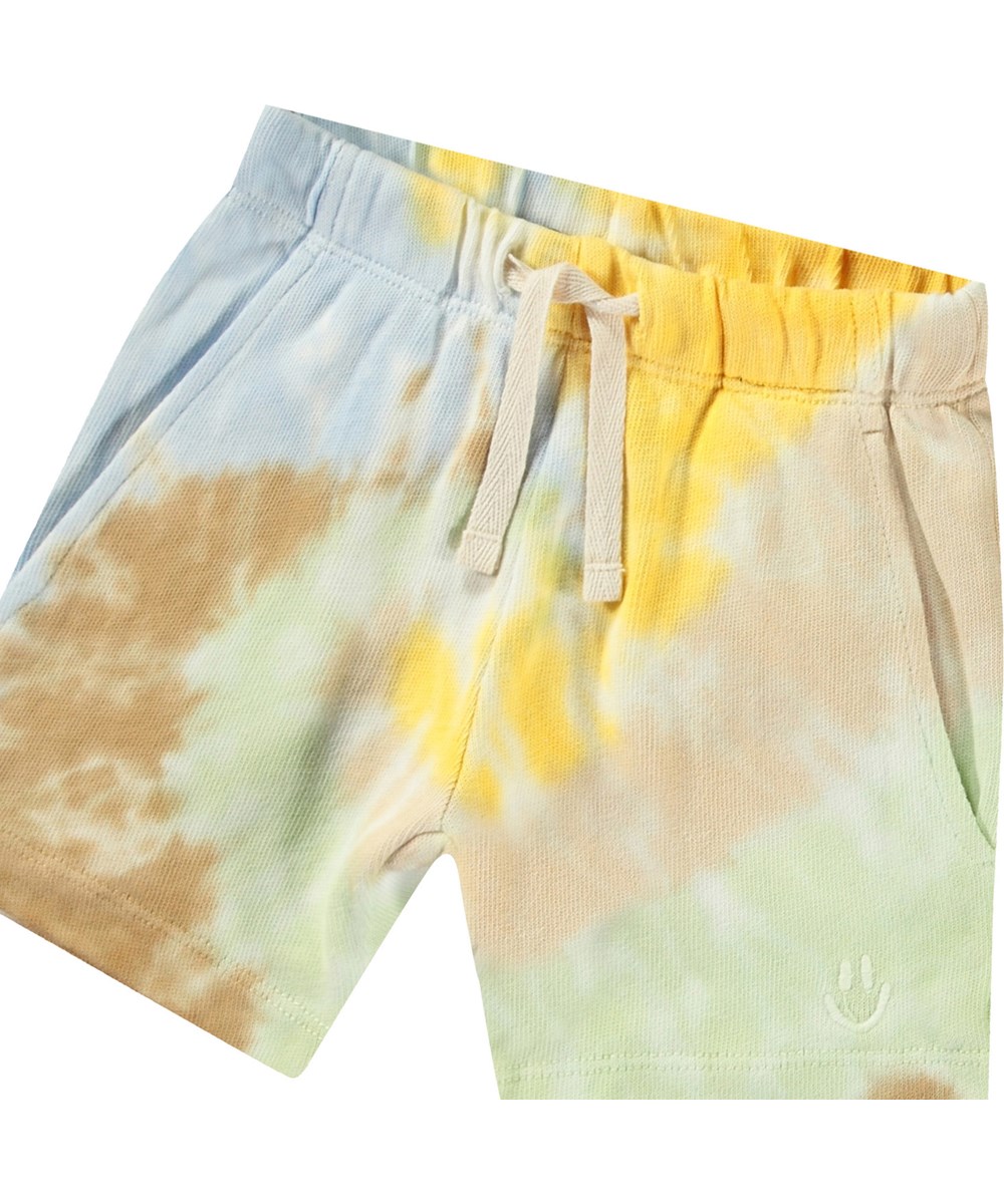 Simms - Tie Dye Swirl - Mjuka ekologiska bomullsshorts för baby. De är i en flerfärgad tie-dye med en broderad smiley.
