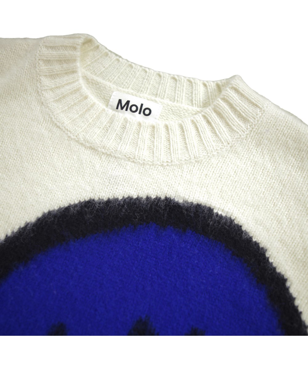 Brian wool - Drippy Smile - Off-white stickad tröja för barn gjord av ull. Tröjan har ett stort blått leende ansikte på framsidan.
