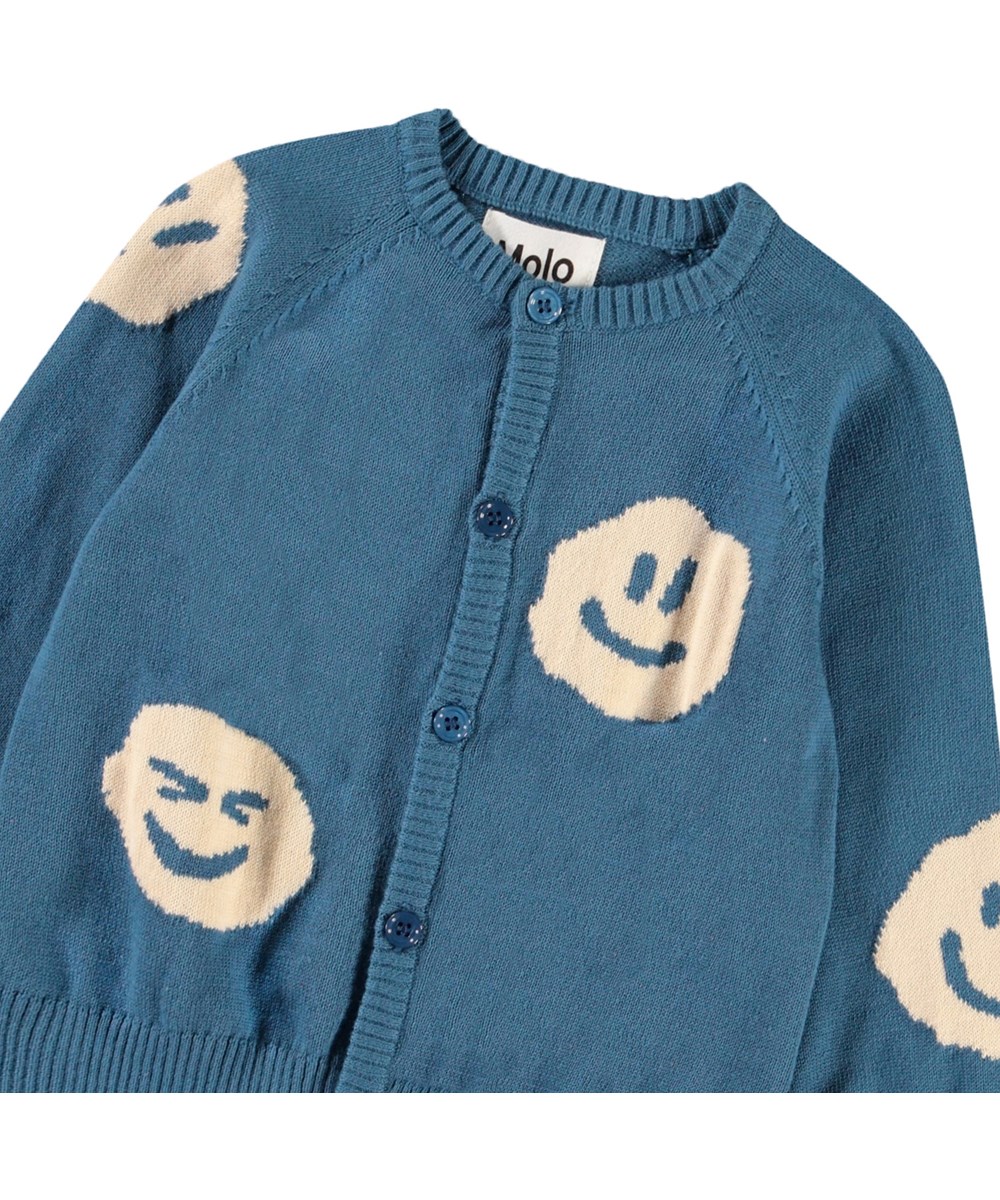 Brody - Lagoa - Stickad kofta för baby i mjuk ekologisk bomull. Koftan är blå med smileys.