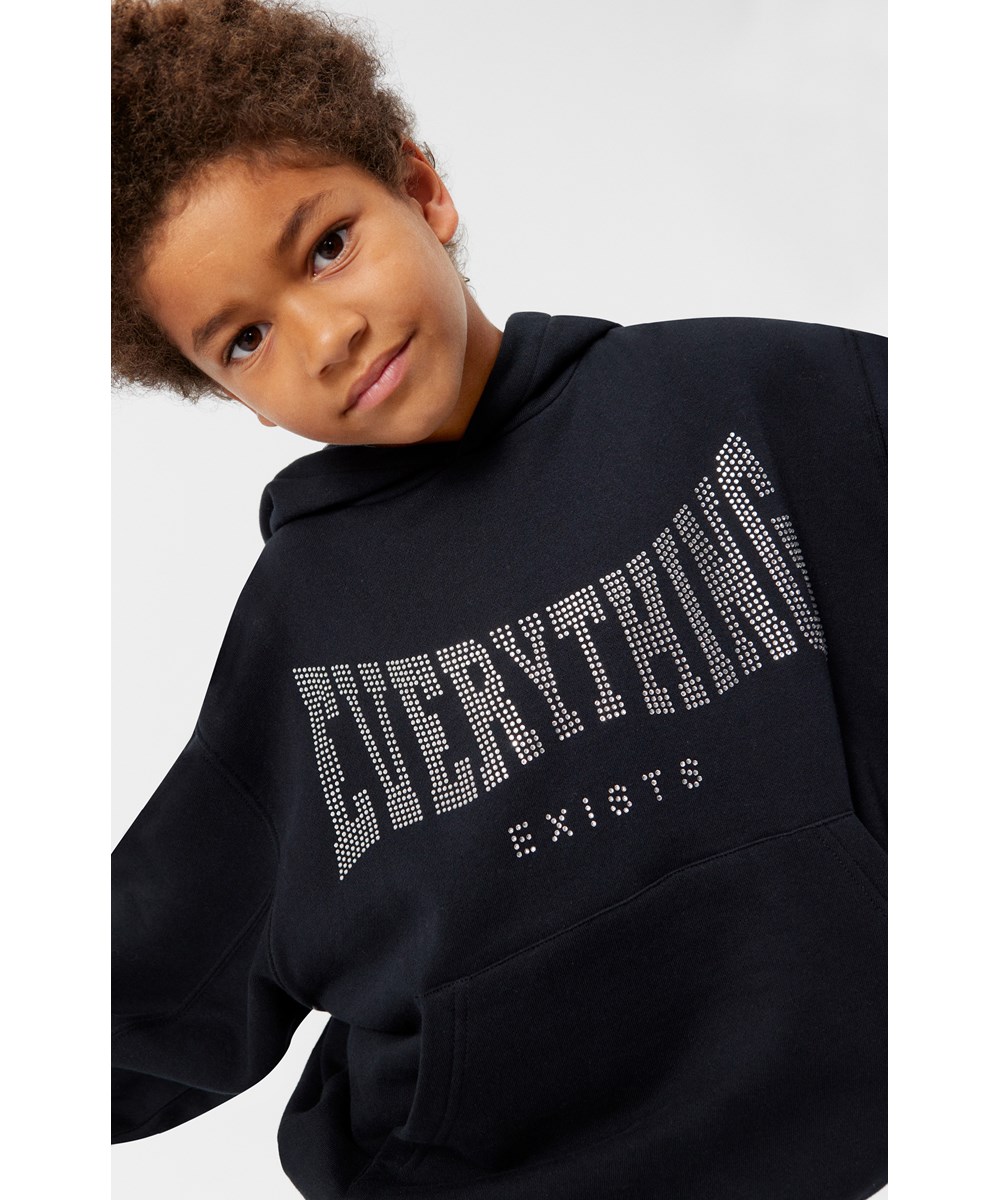 Maxx - Black - Mjuk och varm svart ekologisk bomullshoodie med oversize passform. Paljetter med "Everything exists" på framsidan.