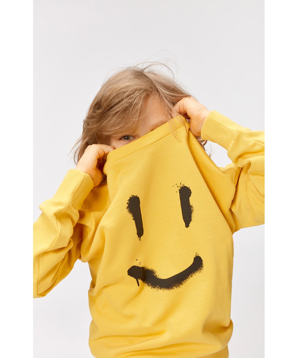 Mik - Hazy Sun - Solgul sweatshirt med svart smileytag.